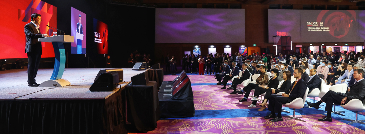 Speaker at a podium on stage, audience seated, "SWITCH" logo displayed.